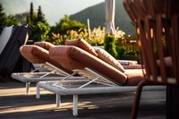 Bequeme Liegestühle mit braunen Kissen auf Terrasse im Sonnenlicht