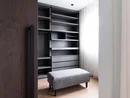 Moderner begehbarer Kleiderschrank mit grauen Regalen und gepolsterter Bank