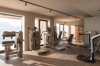 Heller Fitnessraum mit Trainingsgeräten und großen Fenstern mit Bergblick