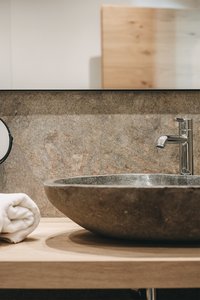 Badezimmer mit steinernem Waschbecken und verchromtem Wasserhahn