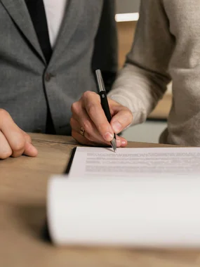 Persona che firma un documento mentre un'altra persona è accanto a lei