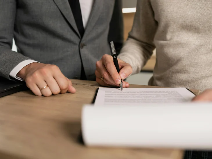 Persona che firma un documento mentre un'altra persona è accanto a lei