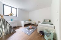Kinderzimmer mit zwei Betten, Tipi-Zelt und Spielzeug auf Holzboden