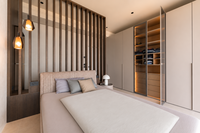 Modernes Schlafzimmer mit Doppelbett, Holzlamellenwand und offenem Kleiderschrank