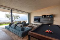 Modernes Wohnzimmer mit Billardtisch und Panoramafenster mit Seeblick