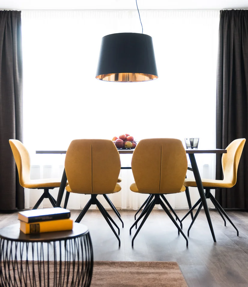 Moderner Essbereich mit gelben Stühlen, schwarzer Pendelleuchte und Sofa