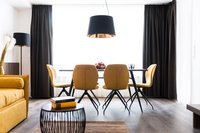 Moderner Essbereich mit gelben Stühlen, schwarzer Pendelleuchte und Sofa