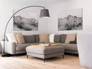 Gemütliche Sitzecke mit grauem Ecksofa, Hocker, Stehlampe und Bergbildern