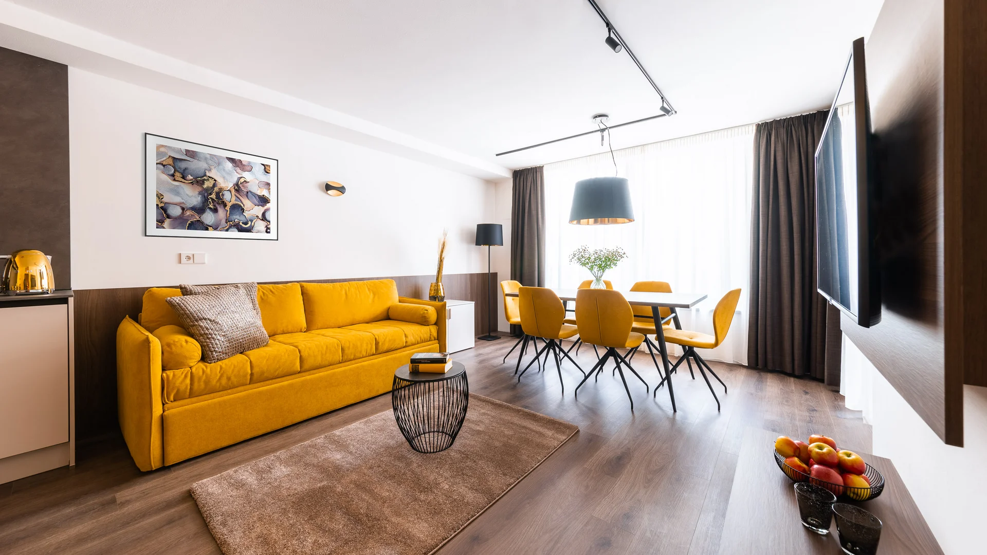 Modernes Wohnzimmer mit gelbem Sofa und Essbereich mit Sesseln