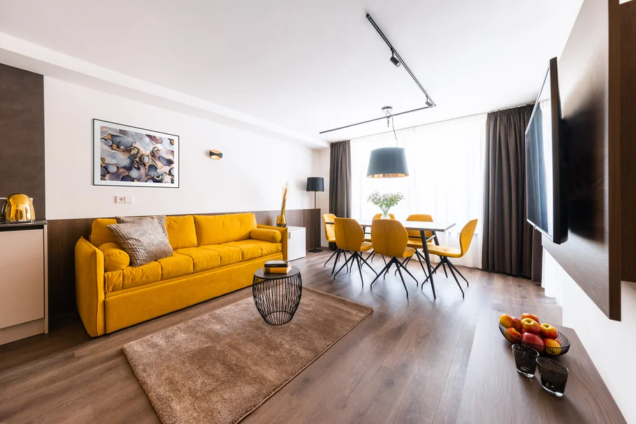 Modernes Wohnzimmer mit gelbem Sofa und Essbereich mit Sesseln