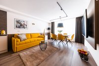 Modernes Wohnzimmer mit gelbem Sofa und Essbereich mit Sesseln