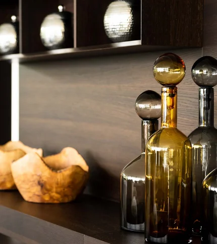 Dekorative Glasflaschen und Holzschalen auf dunklem Regal