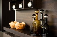Dekorative Glasflaschen und Holzschalen auf dunklem Regal