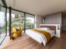Modernes Schlafzimmer mit großen Fenstern und gelbem Sessel