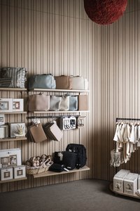 Regale mit Taschen, Kleidung und Babyspielzeug vor Holzvertäfelung