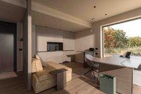 Modernes Zimmer mit Sofa, Schreibtisch, Küchenzeile und großem Fenster zum Garten