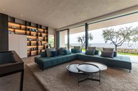 Moderner Wohnbereich mit großem Sofa und Blick auf Terrasse mit Bäumen