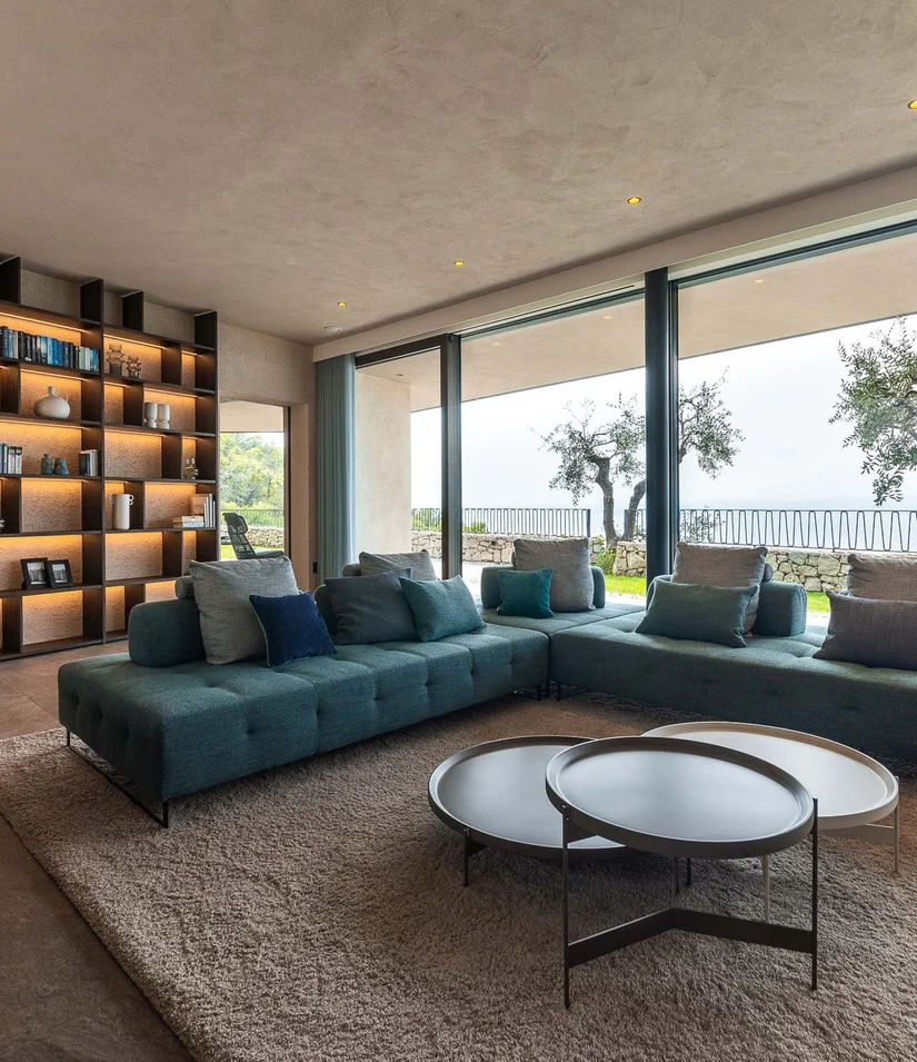 Moderner Wohnbereich mit großem Sofa und Blick auf Terrasse mit Bäumen