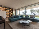 Moderner Wohnbereich mit großem Sofa und Blick auf Terrasse mit Bäumen