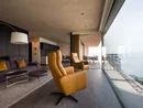 Modernes Wohnzimmer mit Ledersesseln und Meerblick durch Panoramafenster