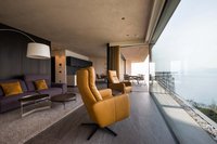 Modernes Wohnzimmer mit Ledersesseln und Meerblick durch Panoramafenster