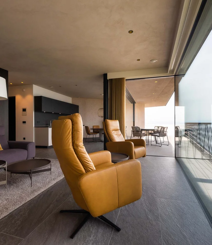 Modernes Wohnzimmer mit Ledersesseln und Meerblick durch Panoramafenster