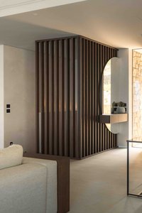 Modernes Wohnzimmer mit dunkler Holzlamellenwand, rundem Durchgang und hellem Sofa