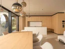 INTERIOS. Il tuo studio di interior design. Zona giorno open space con tavolo in legno, isola cucina, lampade sospese e divano bianco