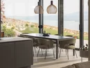 INTERIOS. Il tuo studio di interior design. Zona pranzo luminosa con lampade a sospensione e vista su giardino e lago