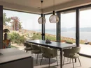 INTERIOS. Il tuo studio di interior design. Sala da pranzo luminosa con tavolo, sedie e vista sul lago e sulle montagne dalle grandi finestre