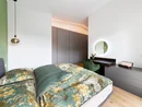Modernes Schlafzimmer mit Blumenbettwäsche, Schreibtisch und runder beleuchteter Spiegel
