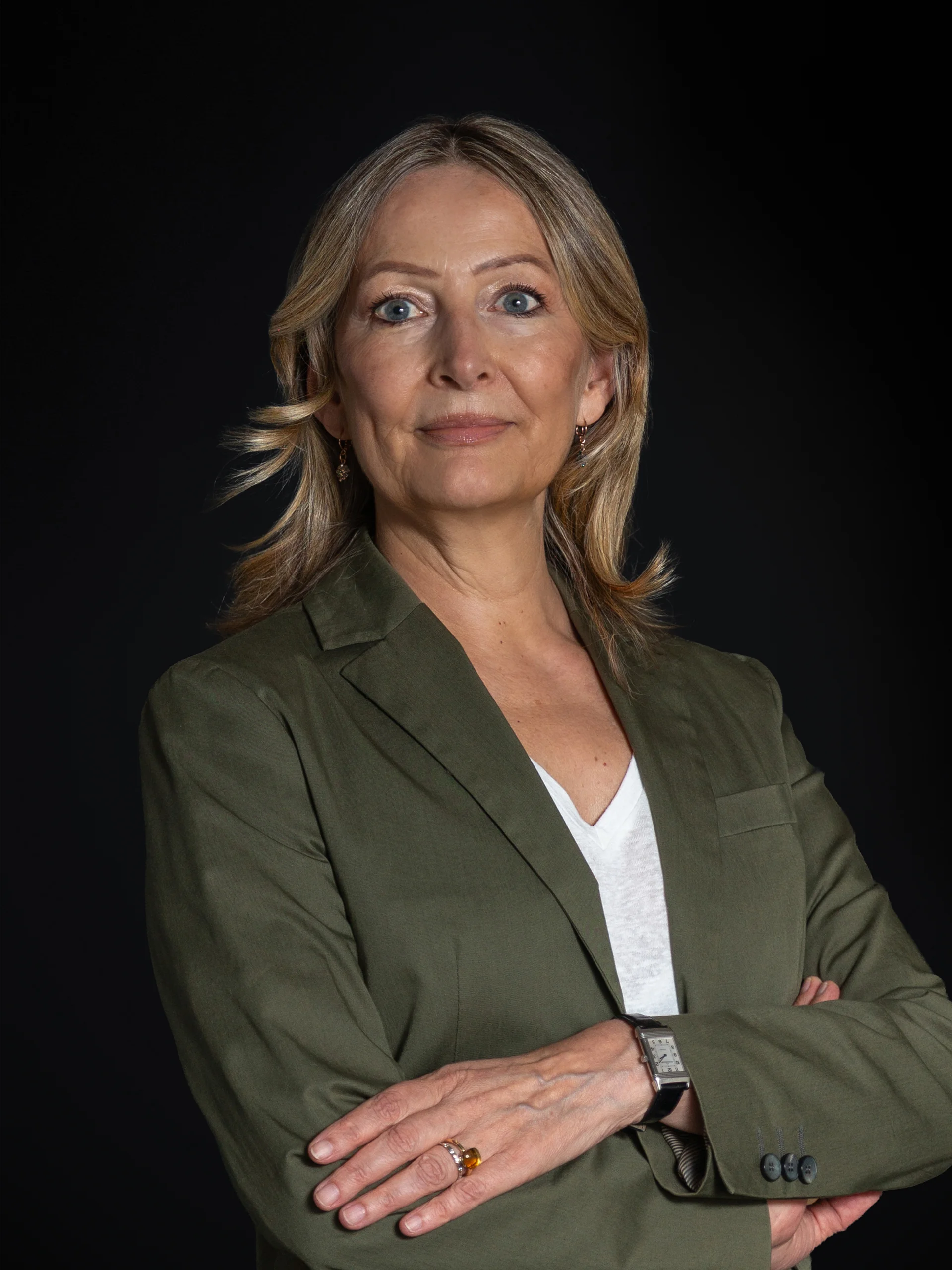 INTERIOS. Il tuo studio di interior design. Ritratto di una donna con le braccia incrociate su sfondo scuro