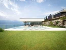 Moderner Poolbereich mit weißen Liegestühlen vor Haus und Seeblick