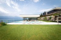Moderner Poolbereich mit weißen Liegestühlen vor Haus und Seeblick
