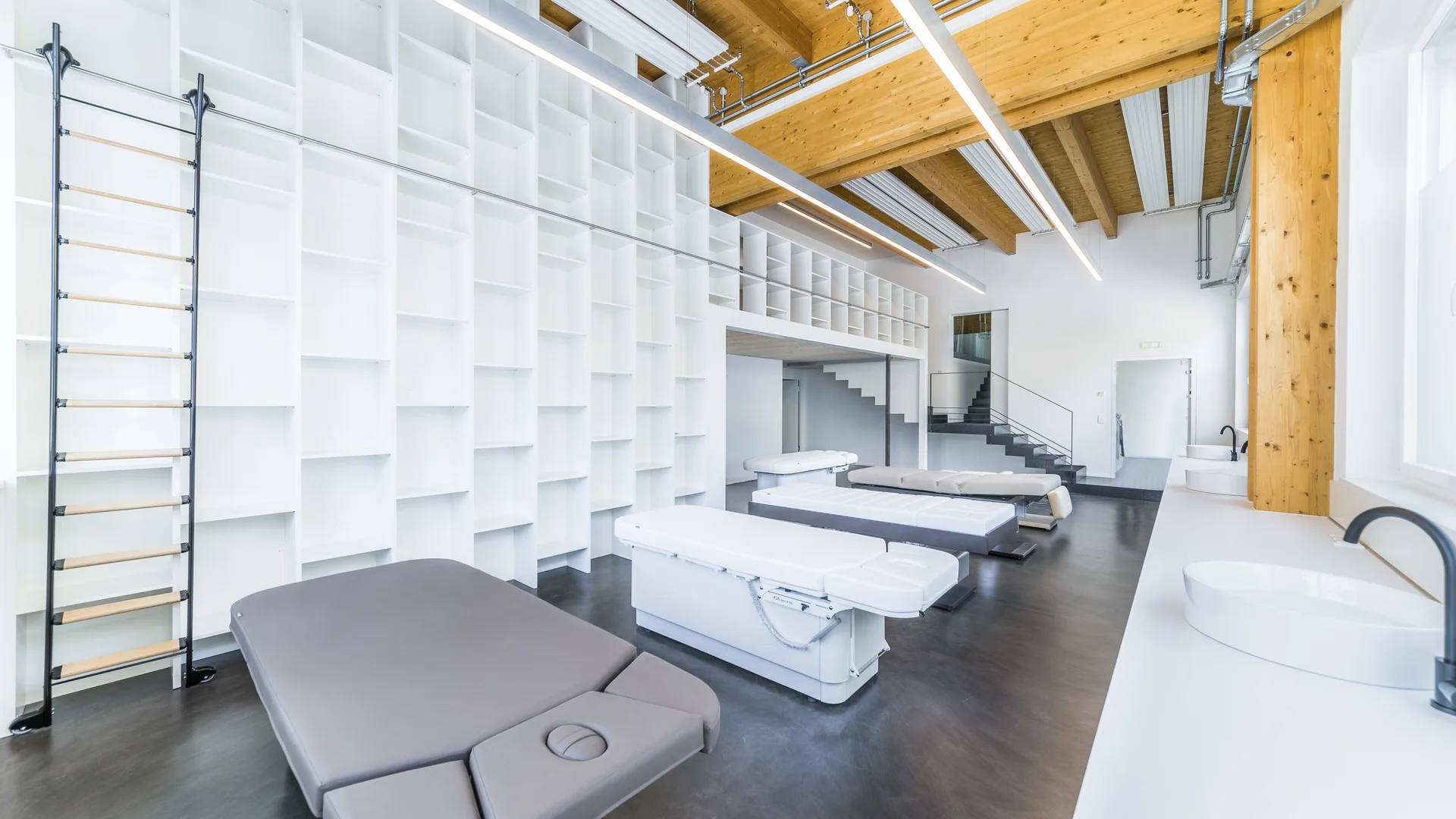 Moderner Behandlungsraum mit Therapieliegen und Holzdecke