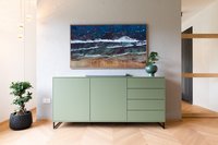Grüner Schrank vor weißer Wand mit Meeresbild und Pflanze im modernen Raum