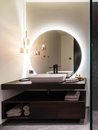 Modernes Badezimmer mit beleuchtetem Spiegel und begehbarer Dusche mit grauen Fliesen