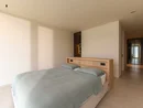 INTERIOS. Il tuo studio di interior design. Camera da letto luminosa con letto matrimoniale, coperta grigia e corridoio adiacente