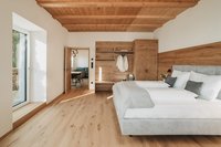 Modernes Schlafzimmer mit Holzboden, Holzdecke und Garderobe mit weißen Kleidern