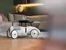 Weißes Kinderrennwagen-Spielzeug auf Holzboden vor einem Sofa