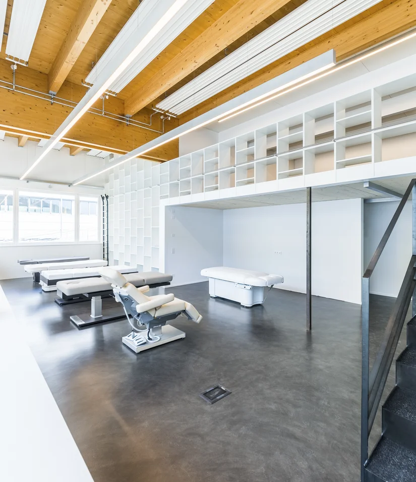 Moderner Behandlungsraum mit Liegen, Waschbecken und Holzdecke