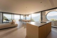 Modernes Wohnzimmer mit Küche, Esstisch und Panoramablick auf See und Berge