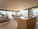 INTERIOS. Il tuo studio di interior design. Moderno soggiorno con cucina, tavolo da pranzo e vista panoramica sul lago e sulle montagne
