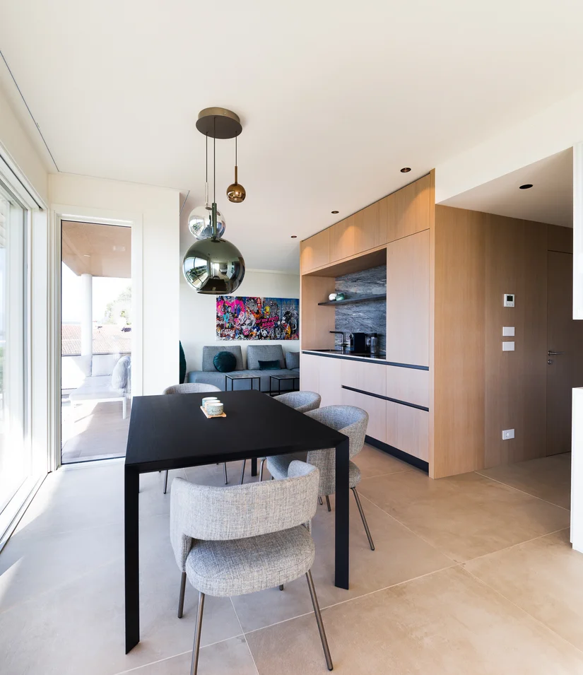 Moderner Essbereich mit schwarz Tisch, grauen Stühlen und großem Fenster zur Terrasse